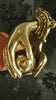 Gold finish brass hand door knocker styled in a dark vintage setting