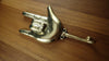Side view of a brass hand gesture wall hook on wood, showing the curved hook shape and detailed hand gesture design.
