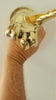 front view solid brass hand fingering gesture with human hand in front of a white wall