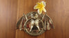 A brass bat wall ring with a yellow flower on a wooden surface