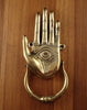 Gold brass hamsa hand door knocker mounted on wooden surface showing full front view