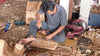 Balinese artisan hand carving wooden Om symbol in Ubud Bali workshop – showing traditional wood carving craft process – handmade om wall hanging yoga meditation spiritual home decor – UbudGlassandBrass made in Bali Indonesia – authentic hand carved om symbol wall art