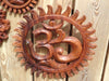 Close-up of hand carved wooden Om wall hanging showing fine carving detail natural wood grain and relief depth on warm wooden surface – solid wood artisan om symbol – yoga meditation spiritual boho home decor – housewarming yoga studio gift – made in Bali UbudGlassandBrass