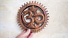 Hand holding wooden Om wall hanging showing real life size and scale – hand carved solid wood om symbol with sunburst border – yoga meditation spiritual boho home decor – om wall decor – meaningful housewarming gift yoga gift – made in Bali Indonesia UbudGlassandBrass